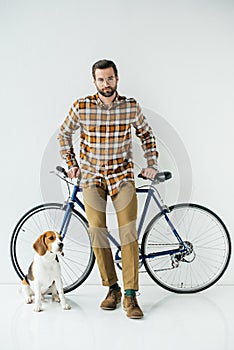 handsome bicycler standing with beagle and looking at camera
