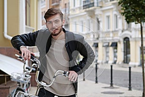 Handsome bike messenger with backpack stands near bicycle and look at camera