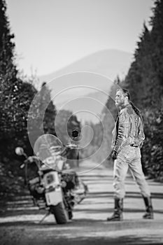 Handsome biker standing by his custom made cruiser motorcycle