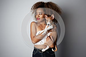 Handsome black african female with afro hair hugging her puppy basenji dog. Love between dog and owner. On white