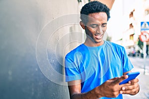 Handsome black african man smiling happy outdoors using smartphone