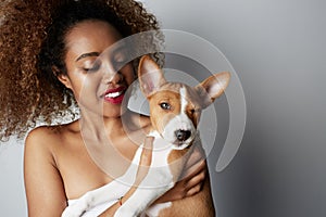 Handsome black american african girl embracing puppy on white background. Studio portrait of white appealing female