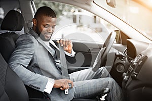 Handsome black businessman fasten seat belt in his car