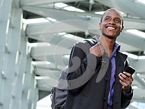 Handsome black businessman traveling with bag and cell phone