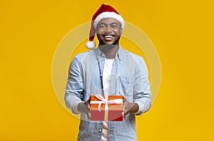 Handsome black guy in red Santa hat holding gift box