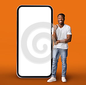 Handsome Black Guy Standing Near Huge Blank Cellphone And Pointing At It