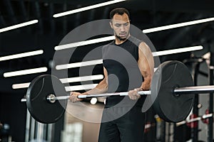 Handsome Black Male Athlete Exercising With Heavy Barbell At Modern Gym Interior