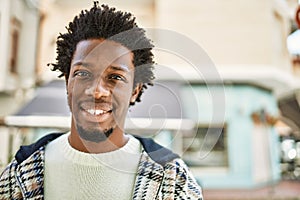 Handsome black man with afro hair and beard smiling happy outdoors