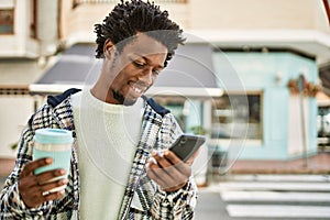 Handsome black man with afro hair smiling happy outdoors using smartphone