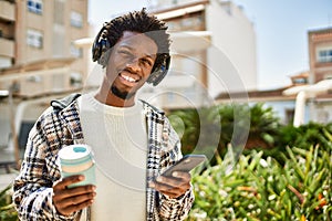 Handsome black man with afro hair wearing headphones listening to music using smartphone