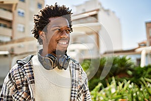 Handsome black man with afro hair wearing headphones smiling happy outdoors