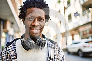 Handsome black man with afro hair wearing headphones smiling happy outdoors