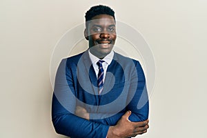 Handsome black man wearing business suit and tie happy face smiling with crossed arms looking at the camera