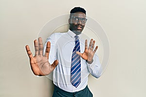 Handsome black man wearing glasses business shirt and tie afraid and terrified with fear expression stop gesture with hands,