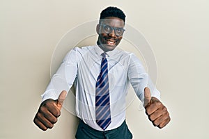 Handsome black man wearing glasses business shirt and tie approving doing positive gesture with hand, thumbs up smiling and happy