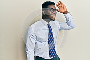 Handsome black man wearing glasses business shirt and tie very happy and smiling looking far away with hand over head