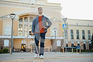 Handsome blind man walks around the city.