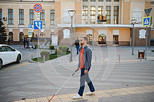 Handsome blind man walks around the city.