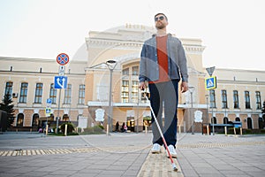 Handsome blind man walks around the city.