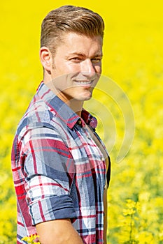 Handsome blond man standing in a yellow field