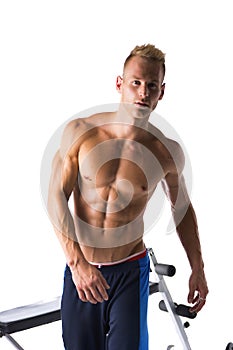 Handsome blond muscular young man next to gym bench