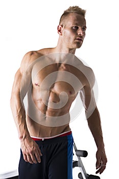 Handsome blond muscular young man next to gym bench