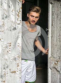 Handsome blond young man opening old door