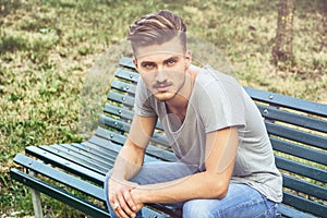 Handsome blond young man sitting on park bench