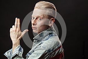 Handsome blonde american man in denim jaket isolated over black background