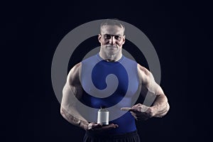 Handsome bodybuilder man with muscular body holds pill jar, steroids