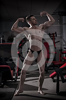 Handsome bodybuilder posing in gym. Perfect muscular male body
