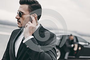 handsome bodyguard of businessman listening message