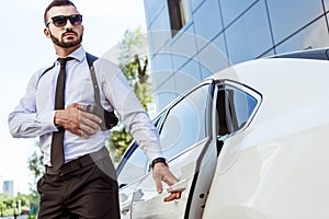 handsome bodyguard touching gun and opening