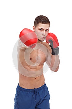 A handsome boxer, with a muscular naked torso, s, strikes in front of him.