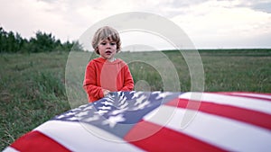 Handsome boy - american patriot child stands with waving national flag on nature. USA, 4th of July - Independence day