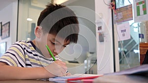Handsome boy do homework while drawing with red and change to green color pencil at apartment lobby of family business