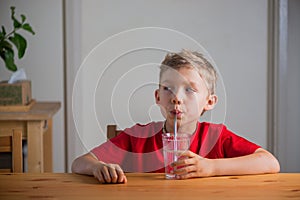 Handsome boy drinks water through drinking straw.