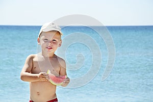 Handsome boy eating slice of watermelon on the