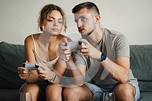 Handsome boy with his fiancee playing video games using joysticks. Man teaches her girlfriend how to play console