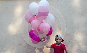 A handsome boy holds laugh in his hand many colored balloons
