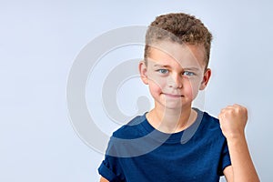 handsome boy looks angry. child is offended, threatens, shows a fist. isolated on white