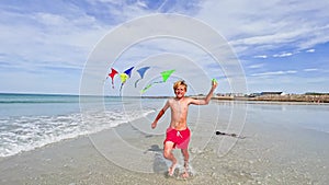 Handsome boy run with colorful set of kites over blue sky
