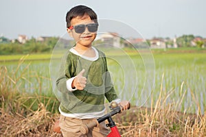 A handsome boy with sunglasses is playing a bicycle