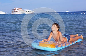 Handsome boy in swimming suit with inflatable matress on the blu photo