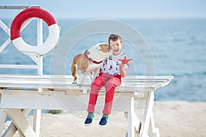 Handsome boy teen happyly spending time together with his friend bulldog on sea side Kid dog holding playing two sea stars close t