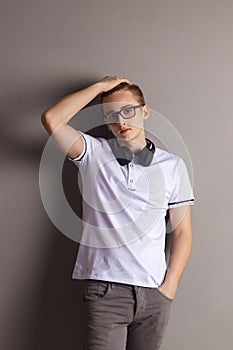 Handsome boy teenager with headphones stands near wall