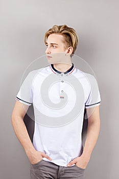 Handsome boy teenager in white shirt stands with hands