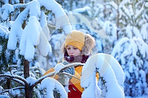 Handsome boy in winterwear walking in snowy winter forest