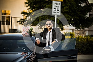 Handsome boyfriend in black suit waiting his girlfriend on street.