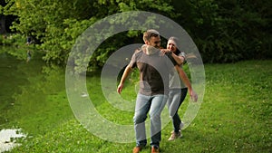Handsome boyfriend carries girl on his back. Romantic couple is having fun outdoors during summer time at the city park